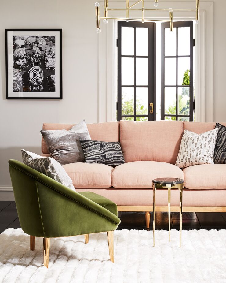 Here the pale pink of the sofa serves as a neutral backdrop for the bold green chair, the gold-and-marble table, and the bevy of black-and-white pillows. 
